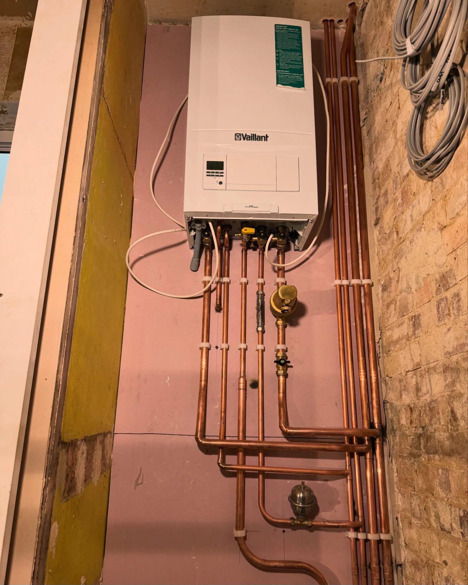 Wall-mounted Vaillant gas combi boiler with neatly clipped copper pipework